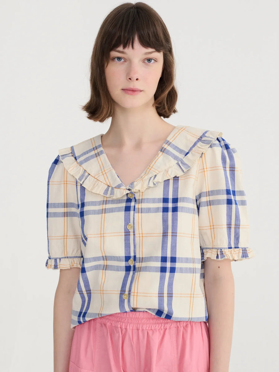 Woman wearing a plaid shirt with ruffled collar on a white background